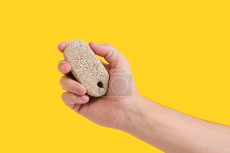 Photo for Pumice stone for cleaning feet and heels, in hand on yellow background - Royalty Free Image