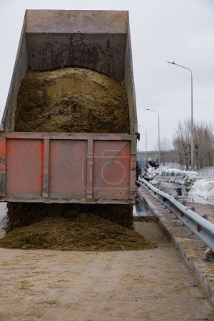 Dump truck unloads sand to fill bags designed protect against flooding
