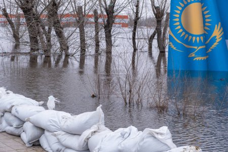 Inondations dans la ville du Kazakhstan en 2024.Sacs de sable et bannière du Kazakhstan noyés dans l'eau de fonte sur fond