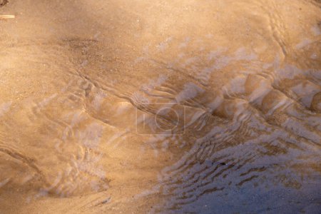 Wasser plätschert auf dem Sand am Strand. Abstrakter Hintergrund