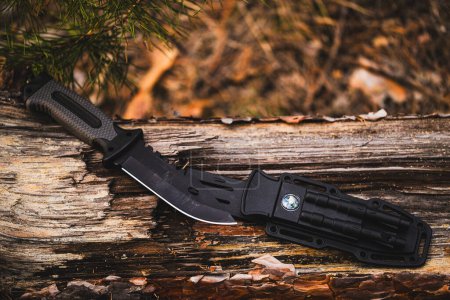 Cuchillo de caza en un tronco en el bosque. Equipo Hunter