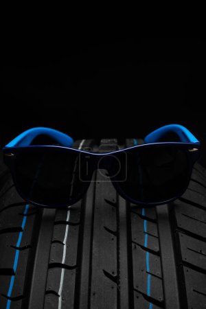 Sunglasses on a car tire, isolated on black background