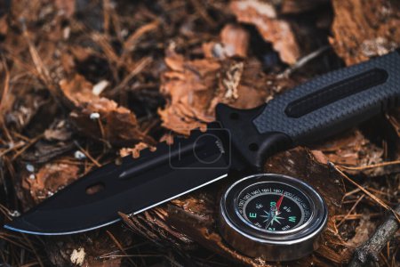Brújula y cuchillo en el suelo en el bosque. concepto de senderismo