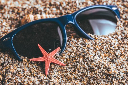 Seesterne und Sonnenbrillen am Strand, Sommerferienkonzept