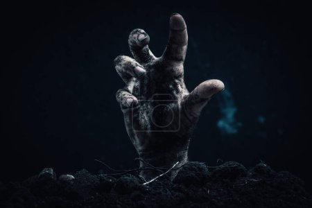 Zombie hand coming out of the ground on a dark background. Horror theme