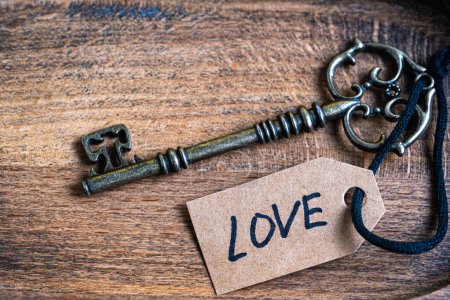 Old key with love tag on a wooden background