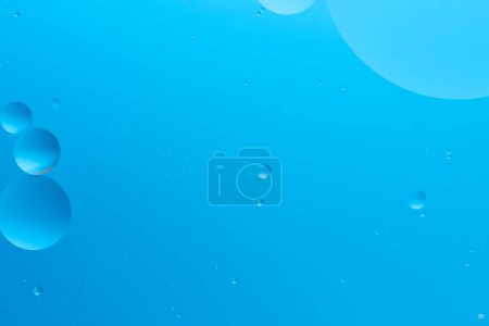 Abstract image with blue bubbles of various sizes on light blue background, creating serene and minimalistic look