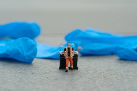 Photo for Miniature people toy figure photography. Cleaning worker with trash bin walking between used rubber latex gloves on the road. Image photo - Royalty Free Image