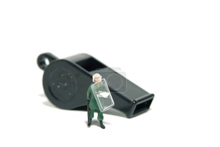Foto de Miniature people toy figure photography. Justice collaborator and whistleblower protection concept. A military anti riot armored army with black whistle. Isolated on white background. Image photo - Imagen libre de derechos