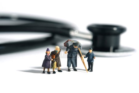 Miniature people toy figure photography. A group of poor family grandpa, grandma, and two grandchildren standing in front of stethoscope. Medical access concept. Image photo