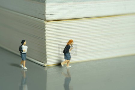 Foto de Personajes miniatura juguete figura fotografía. Dos alumnas corriendo en un corredor de libros. Foto de imagen - Imagen libre de derechos