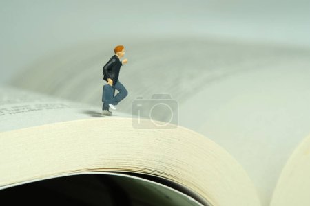 Foto de Personajes miniatura juguete figura fotografía. Un niño alumno corriendo por encima del libro abierto. Foto de imagen - Imagen libre de derechos