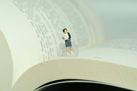 Foto de Personajes miniatura juguete figura fotografía. Una alumna corriendo por encima del libro abierto. Foto de imagen - Imagen libre de derechos