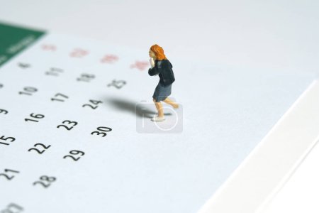 Personajes miniatura juguete figura fotografía. Una alumna corriendo por encima del calendario. Aislado sobre un fondo blanco. Foto de imagen