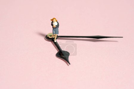 Miniatur winzigen Menschen Spielzeug Fotografie. Eine Schülerin in Schuluniform läuft im Uhrzeigersinn darüber. Vereinzelt auf rosa Hintergrund. Bild Foto