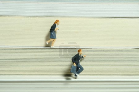 Foto de Personajes miniatura juguete figura fotografía. Dos alumnos y alumnas corriendo en una pila de libros. Foto de imagen - Imagen libre de derechos