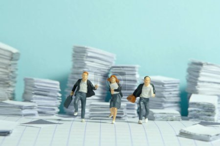 Miniature people toy figure photography. Homework concept. The group of pupil students running on paperwork task document pile stack. Image photo