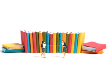 Miniature personnes jouet figure photographie. Deux étudiantes courent devant la rangée de livres. Isolé sur fond blanc. Image photo