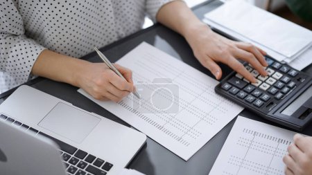 Buchhalterin mit Taschenrechner und Laptop, während sie mit einem Kunden oder Kollegen Steuern zählt. Wirtschaftsprüfungsteam, Finanzberater.
