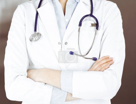Téléchargez les photos : Une jeune femme médecin inconnue se tient debout les bras croisés à la clinique. Concept de médecine pendant la pandémie de coronavirus. - en image libre de droit