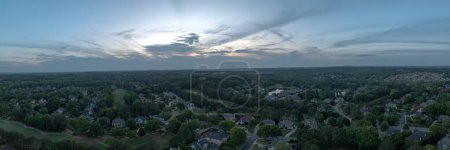Una vista panorámica aérea de 180 grados de una subdivisión de lujo en los suburbios de Estados Unidos filmada durante la puesta del sol en la primavera de 2024