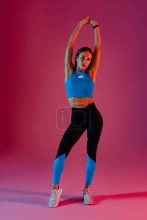 Photo for Active woman wearing sportswear posing with hands raised up on studio background. High quality photo - Royalty Free Image