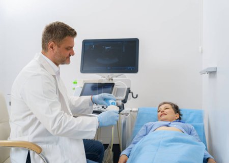 Sonógrafo que aplica gel en el dispositivo de ultrasonido antes del tratamiento con el paciente. Foto de alta calidad