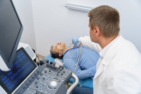 Téléchargez les photos : Femme adulte ayant un examen thyroïdien avec échographie au cabinet médical. Concept de soins de santé - en image libre de droit