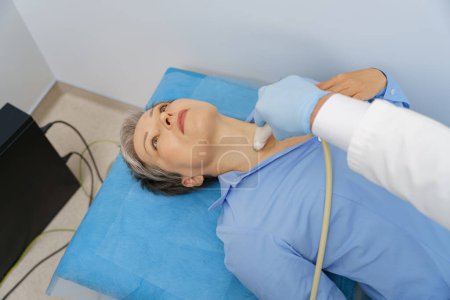 Téléchargez les photos : Femme adulte ayant un examen thyroïdien avec échographie au cabinet médical. Concept de soins de santé - en image libre de droit