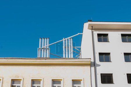 Foto de Tubos de gas, tubos de escape y ventilación en el techo de un edificio residencial moderno, tubos de drenaje en la pared. - Imagen libre de derechos