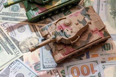 Military tanks, American dollars, close-up.  Concept: arms spending, military aid, arms and ammunition trade, money loan, war in Ukraine.