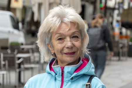 Foto de Retrato callejero de una anciana rubia de 60-70 años sobre el fondo borroso de la calle, multitudes de personas en una de las ciudades europeas. - Imagen libre de derechos
