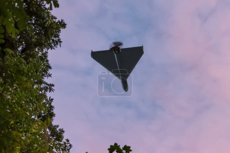Photo for Bottom view of Russian army drone combat drone "Shahid" in the sky against foliage background, flying over war territory in Ukraine, drone attack, - Royalty Free Image