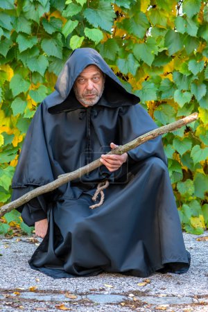 Téléchargez les photos : Helloven vacances, un homme habillé comme un moine avec un bâton en bois sur un fond de heleni. - en image libre de droit
