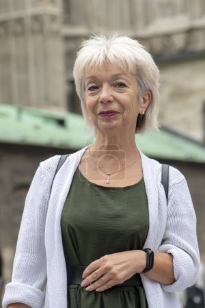 Foto de Retrato callejero de una anciana de 65-70 años en el contexto de la antigua arquitectura histórica europea. - Imagen libre de derechos
