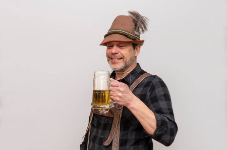 Älterer bärtiger Mann mit Hut will Bier mit Schaum trinken, Bierfest in Österreich und Deutschland.