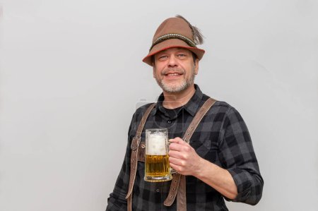 Mann mit Jagdhut und einem Glas Bier in der Hand auf weißem Hintergrund. Bierfest in Österreich und Deutschland.