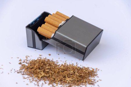 A plastic cigarette case next to a pile of scattered tobacco on a white background.