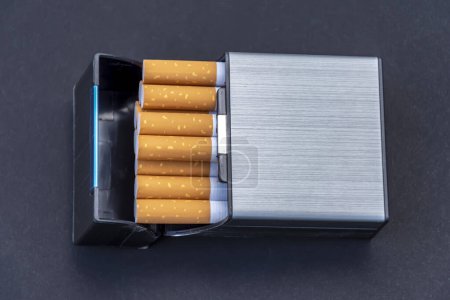 In a plastic cigarette case with cigarettes on a black background, top view.