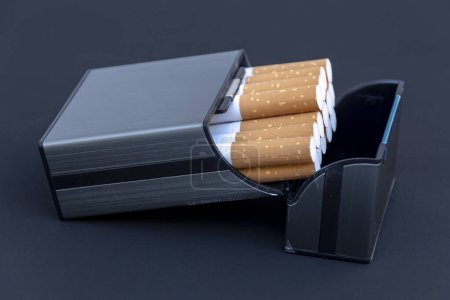 Una pitillera con cigarrillos sobre un fondo negro, cuidadosamente apilada en el interior, lista para ser encendida y fumada.