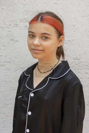 Portrait of a 12 year old girl in black pajamas on a light colored background.