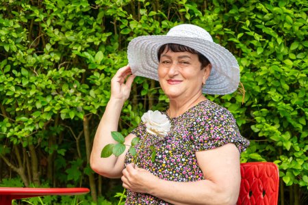 Retrato de mujer hermosa de 60-70 años de edad en fieltro sombrero blanco sobre fondo borroso de la naturaleza. Pensionista con estilo, vida activa de las personas mayores.