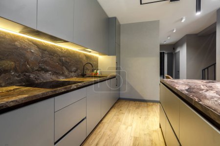 Photo for Modern luxury apartment with a free layout in a loft style in gray and dark colors. Stylish kitchen area with an island marble countertop - Royalty Free Image