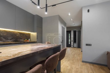 Photo for Modern luxury apartment with a free layout in a loft style in gray and dark colors. Stylish kitchen area with an island and marble countertop - Royalty Free Image