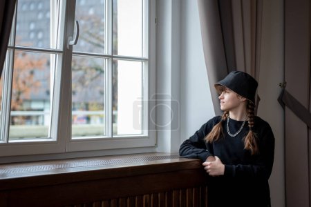 Téléchargez les photos : Portrait d'une belle jeune fille près de la fenêtre dans un chapeau - en image libre de droit