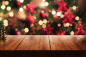 Empty wooden table. Against the background of a blurred Christmas cozy window with bokeh Poster #619938830