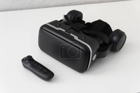 Foto de Casco de realidad virtual y un joystick sobre mesa de fondo blanco. Gafas negras modernas para ver vídeos de 360 grados para un smartphone. - Imagen libre de derechos