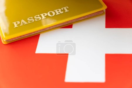 Foto de Bandera de Suiza con pasaporte. Visado de viaje y concepto de ciudadanía. permiso de residencia en el país. un documento amarillo con el pasaporte de inscripción está en la bandera. Primer plano, vista superior - Imagen libre de derechos