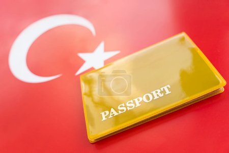 Flagge der Türkei mit Pass. Reisevisum und Staatsbürgerschaftskonzept. Aufenthaltsgenehmigung im Land. Auf der Flagge befindet sich ein gelbes Dokument mit der Aufschrift Pass. Nahaufnahme, Draufsicht