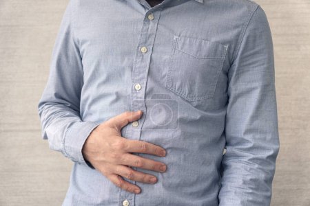 Photo for Abdominal pain. a man holds a sick stomach with his hand. nausea, indigestion. - Royalty Free Image